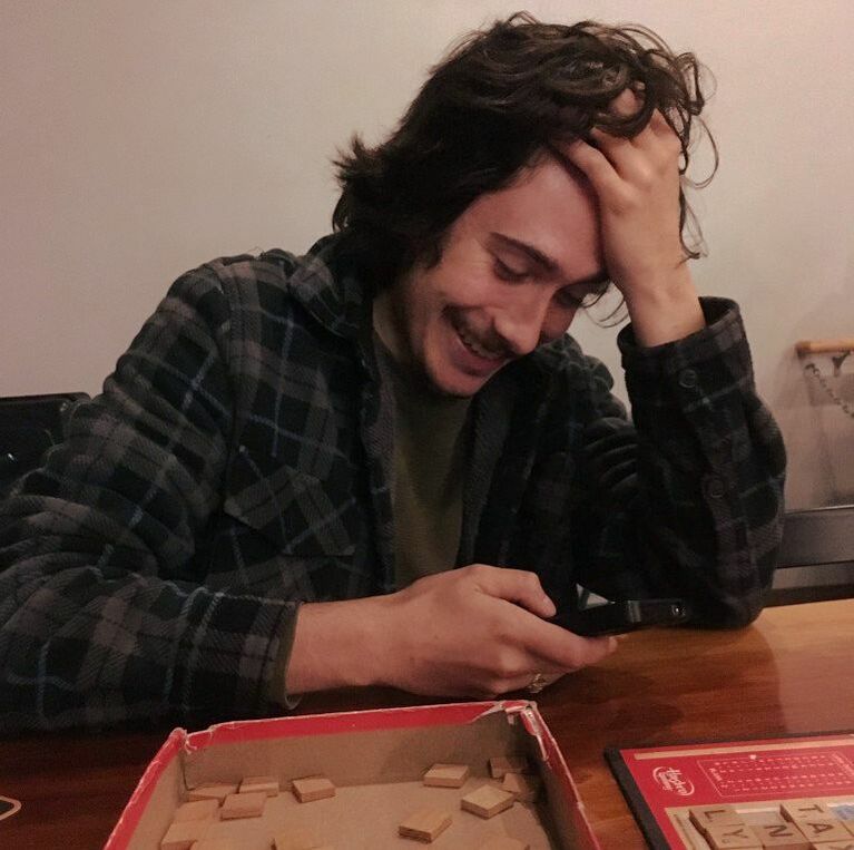 A photo of the author playing Scrabble and checking his phone in an amused way